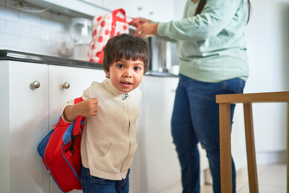 Portrait cute boy with backpack in kitchen