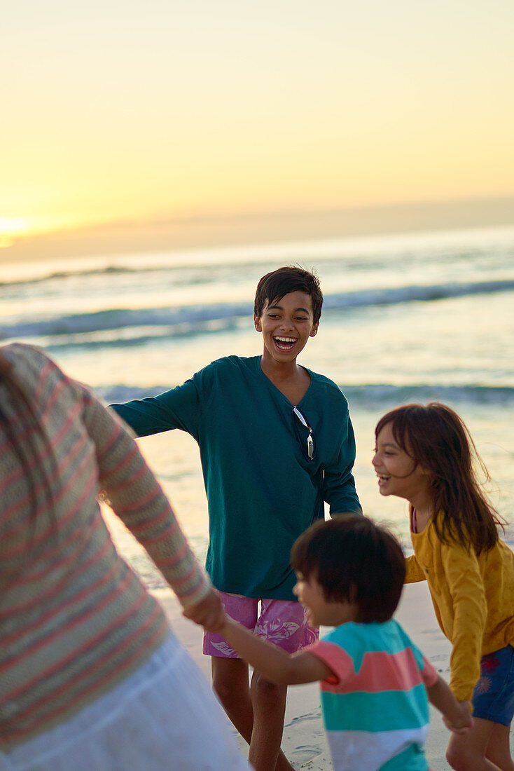 Happy family playing on beach at sunset