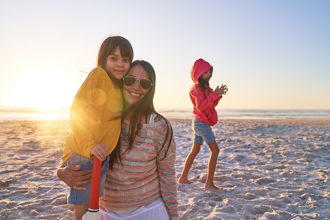 Mother and daughters on sunny beach at sunset