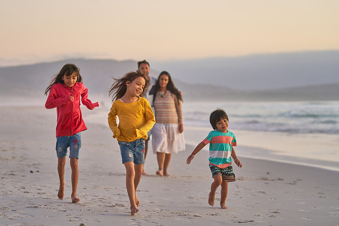 Happy family running on ocean beach