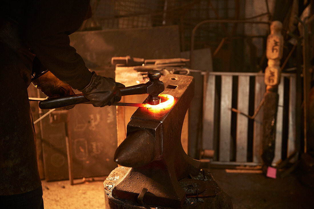 Blacksmith shaping steel on anvil in workshop