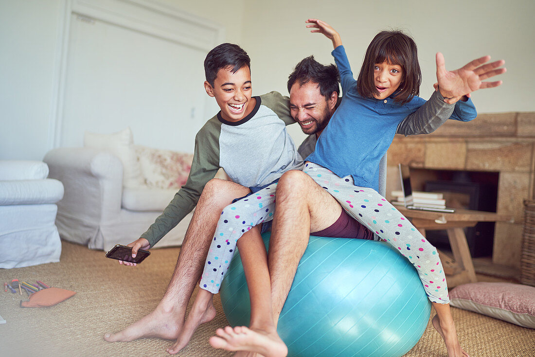Family playing on fitness ball in living room