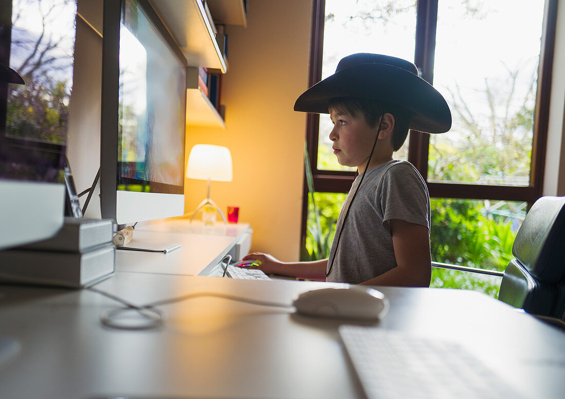 Boy in cowboy hat playing videogame