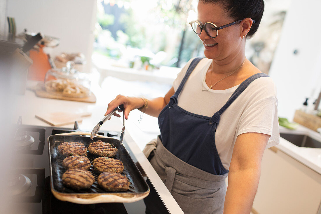 Woman cooking hamburgers on kitchen stove