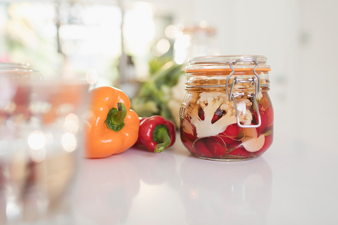 Preserved vegetables in jars on kitchen counter