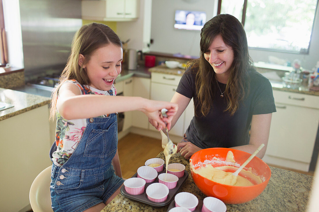 Happy mother and daughter baking cupcakes