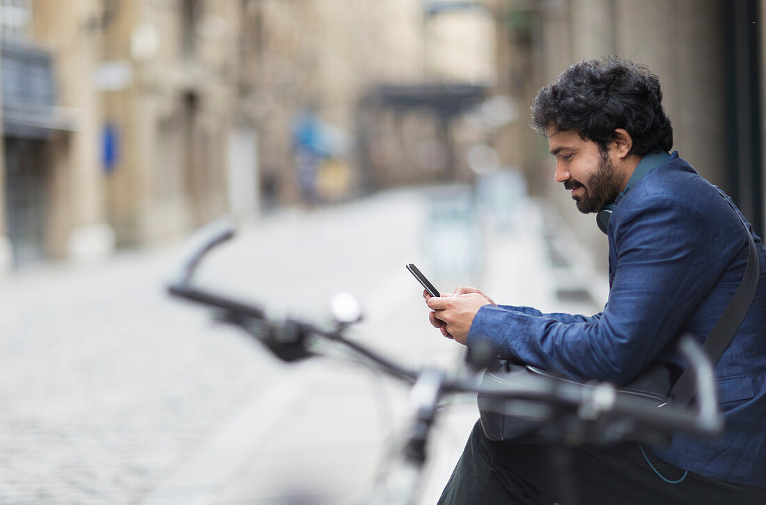 Businessman with bicycle using smart phone