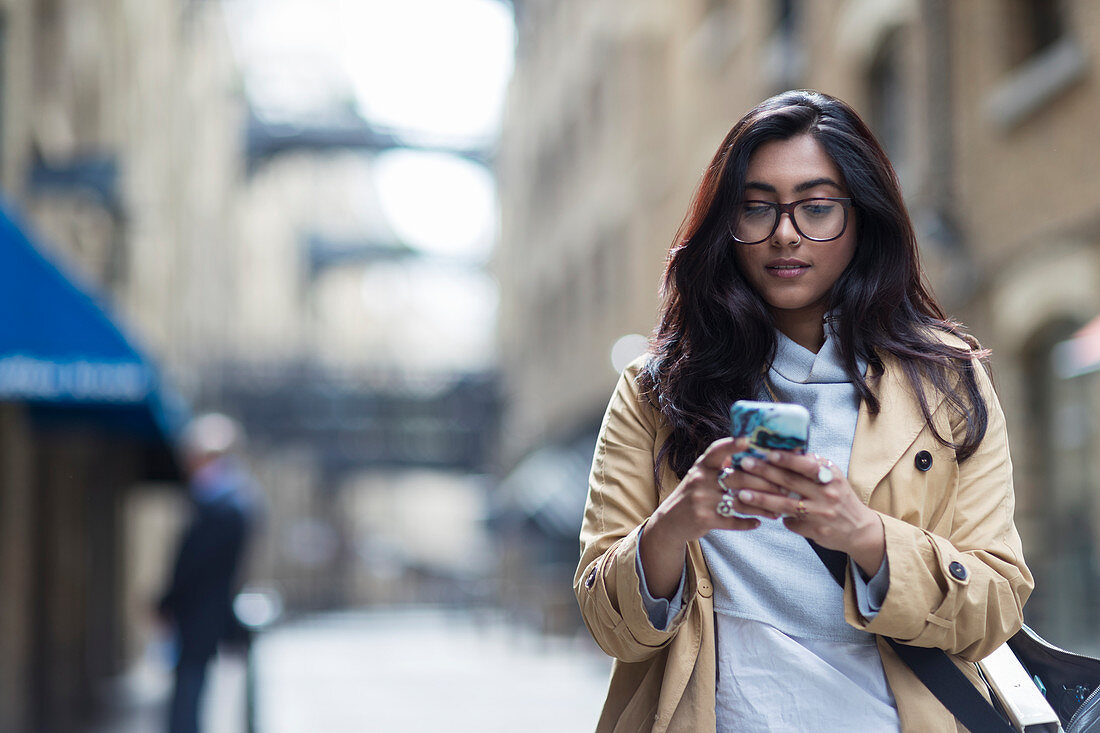 Woman using smart phone on city street