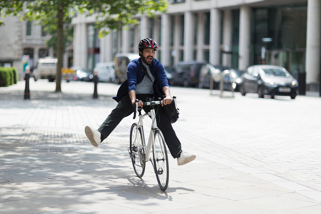 Playful man riding bicycle on city street