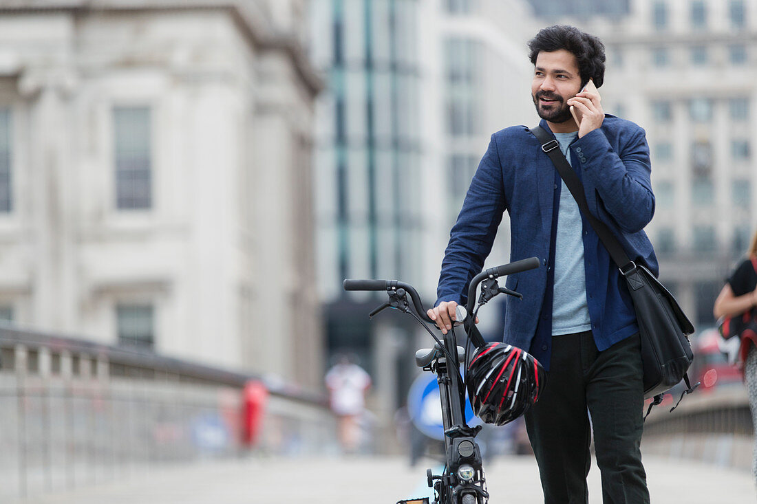 Businessman with bicycle talking on smart phone