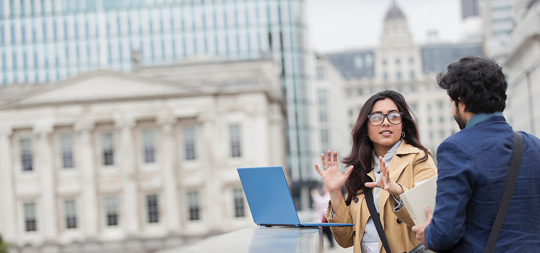 Business people using laptop on city bridge