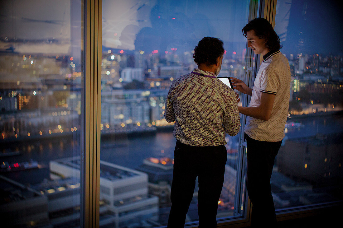 Businessmen with tablet at highrise office window