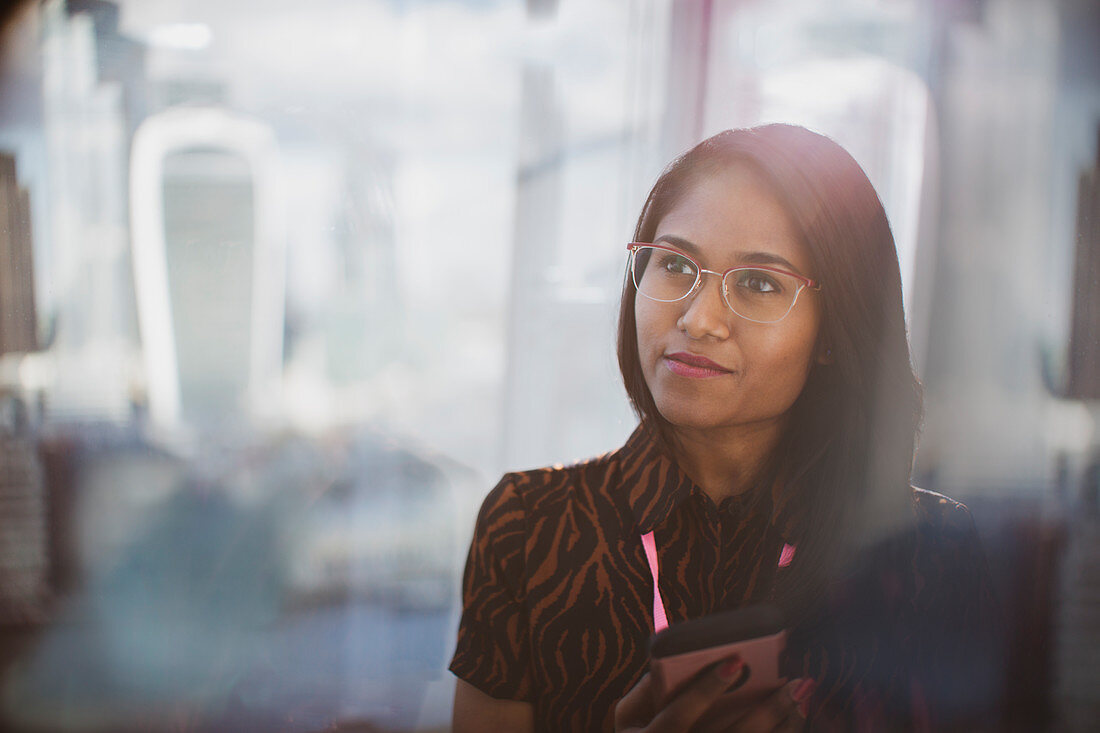 Businesswoman with smart phone in sunny window