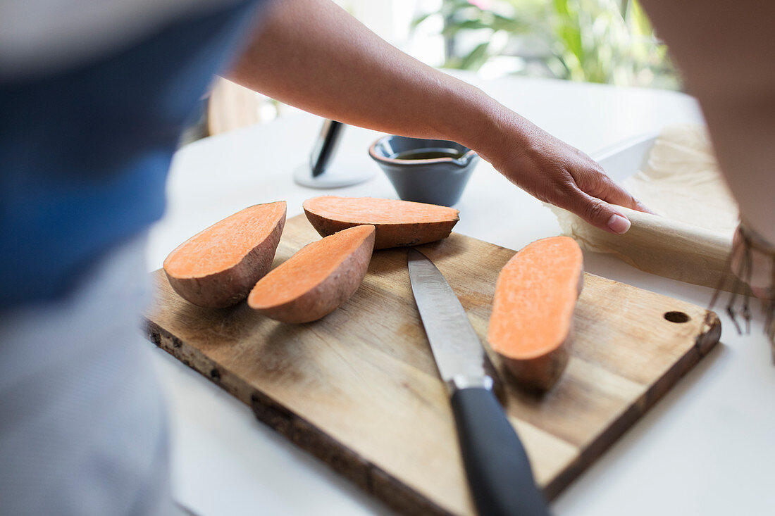 Woman slicing sweet potatoes on cutting board
