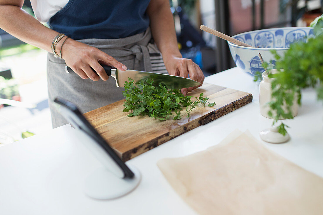 Woman cutting fresh cilantro with knife