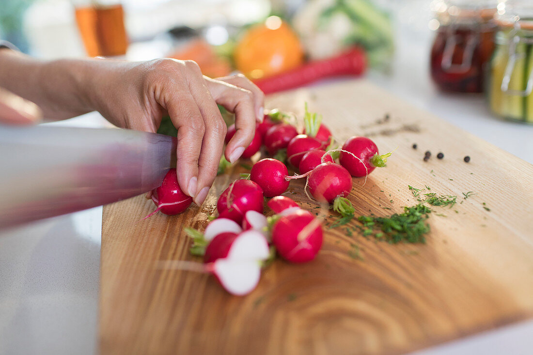 Woman slicing fresh radishes on cutting board