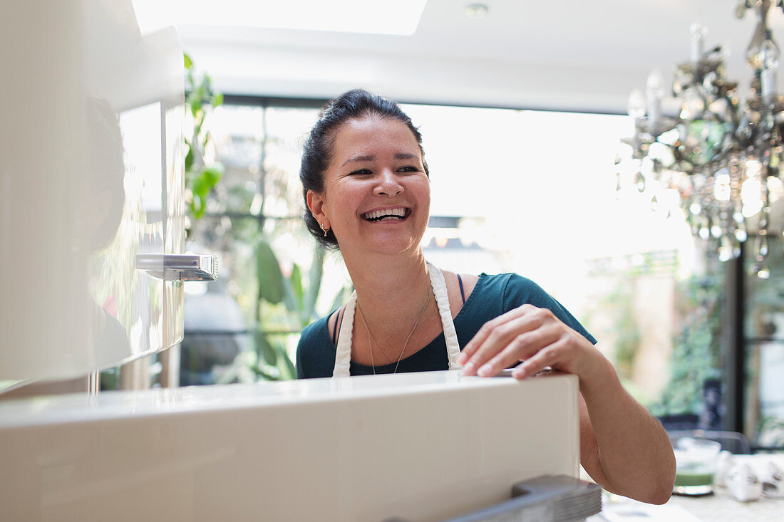 Happy woman laughing at open refrigerator