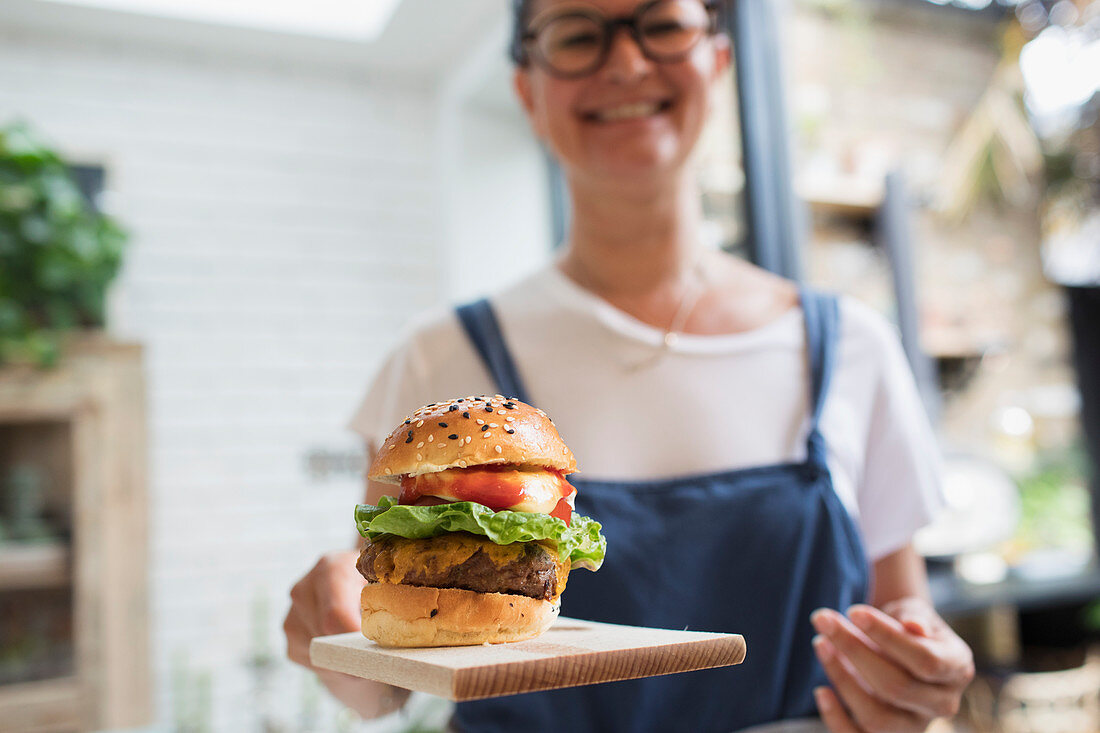 Portrait woman with cheeseburger on cutting board