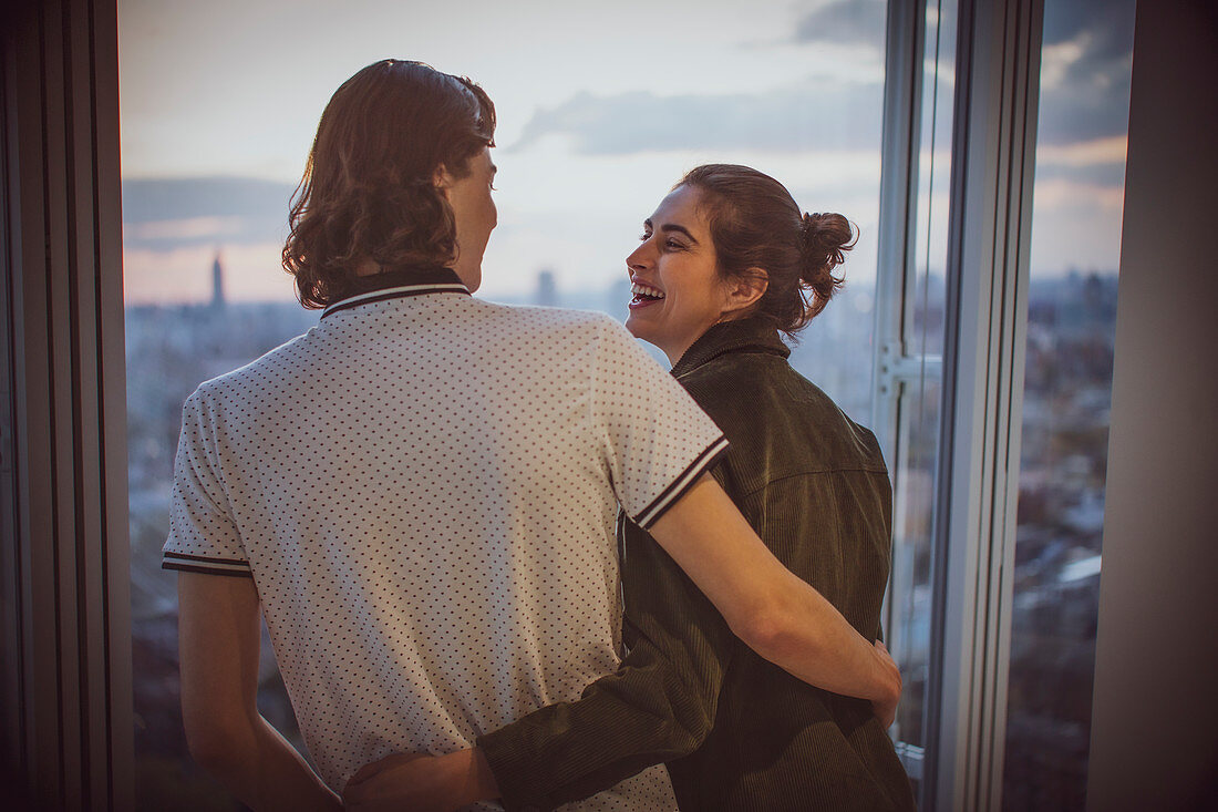 Happy young couple hugging at highrise window
