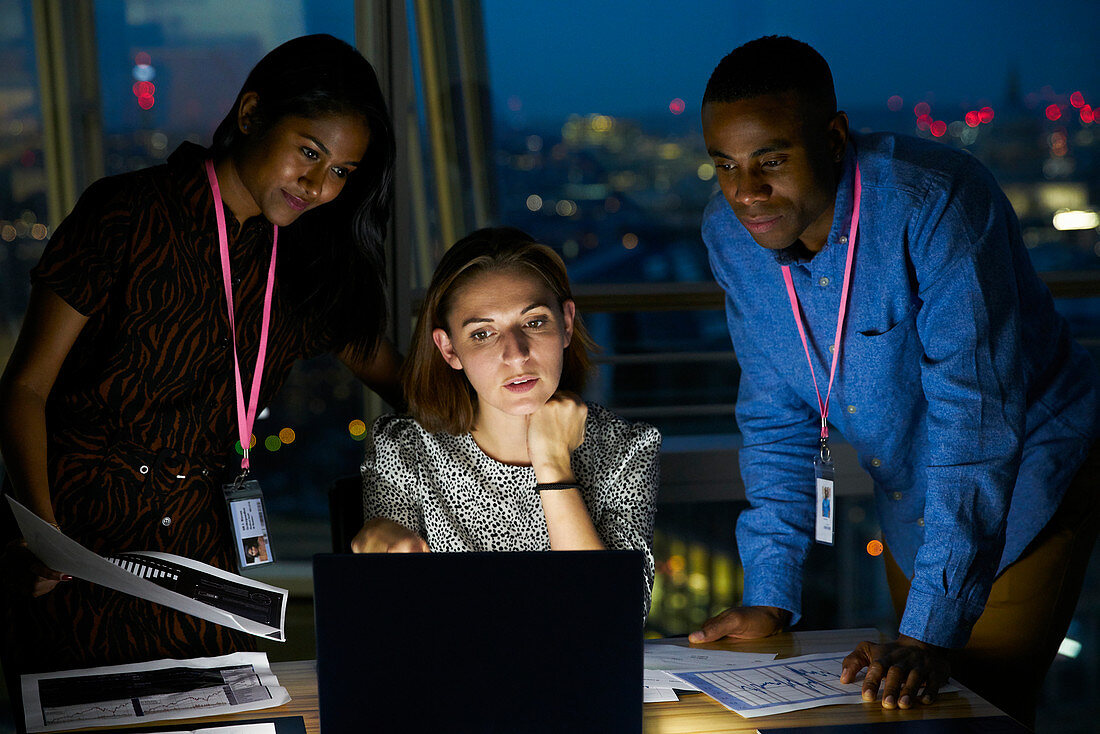 Business people working late at laptop in office