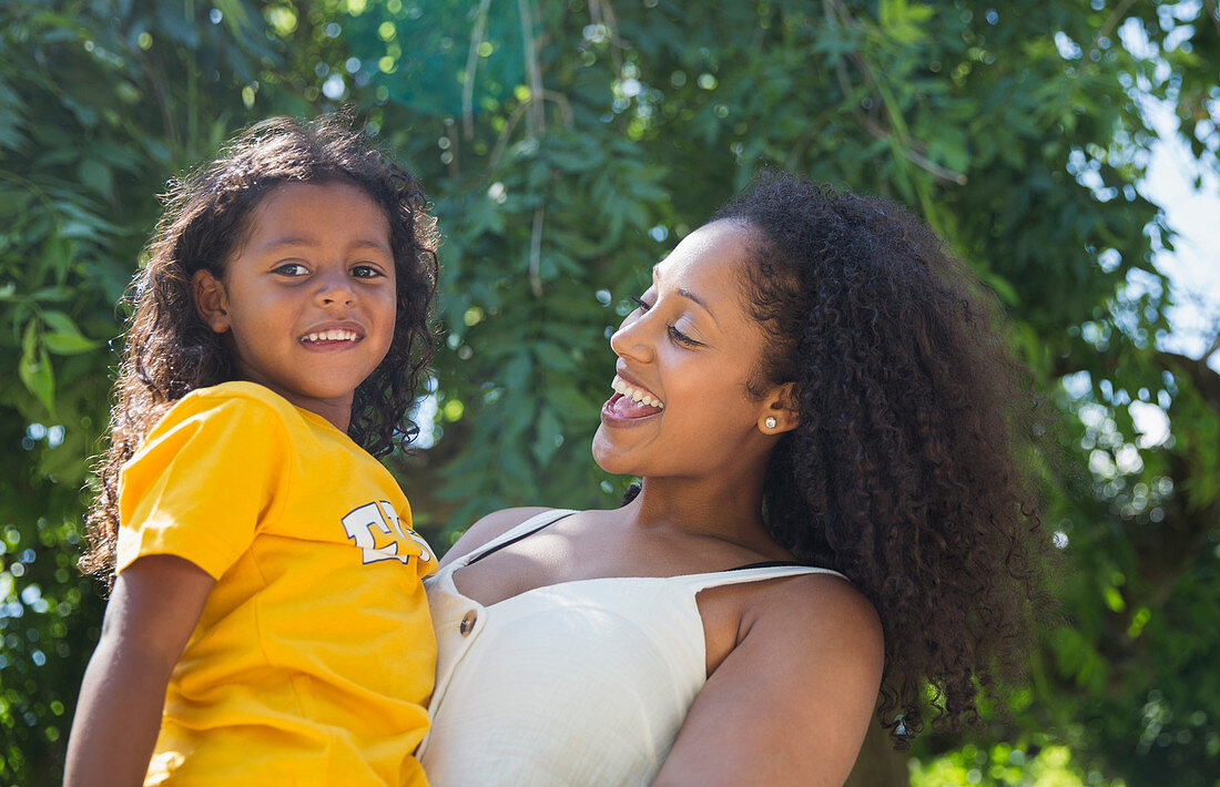 Mother and daughter under tree in summer park