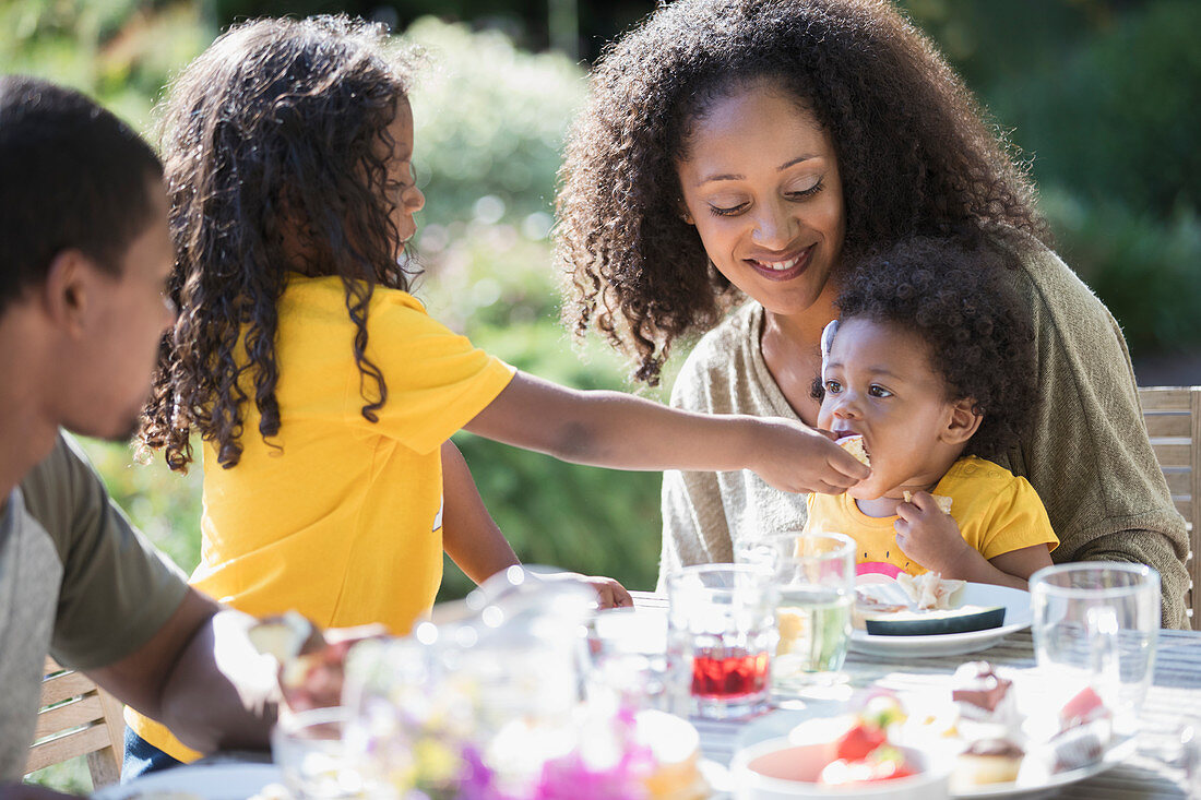 Family eating lunch at sunny summer patio table