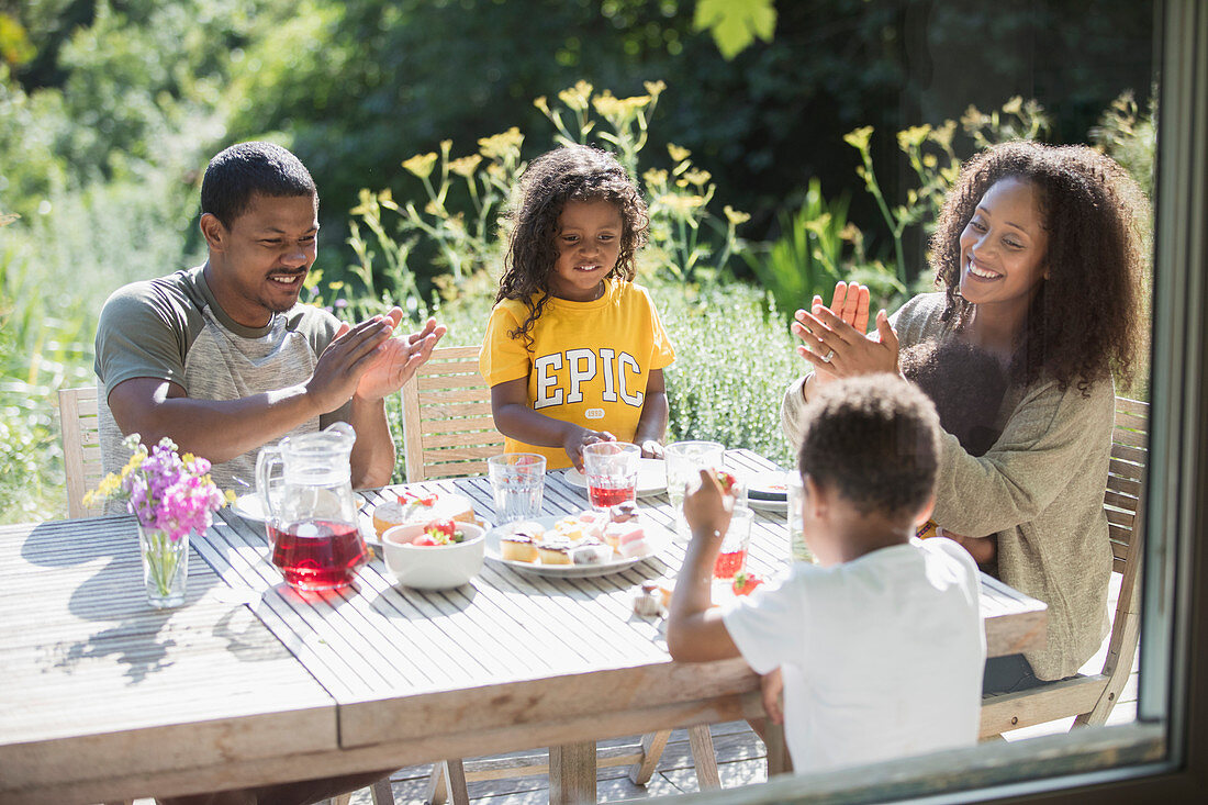 Family clapping and eating at summer patio table
