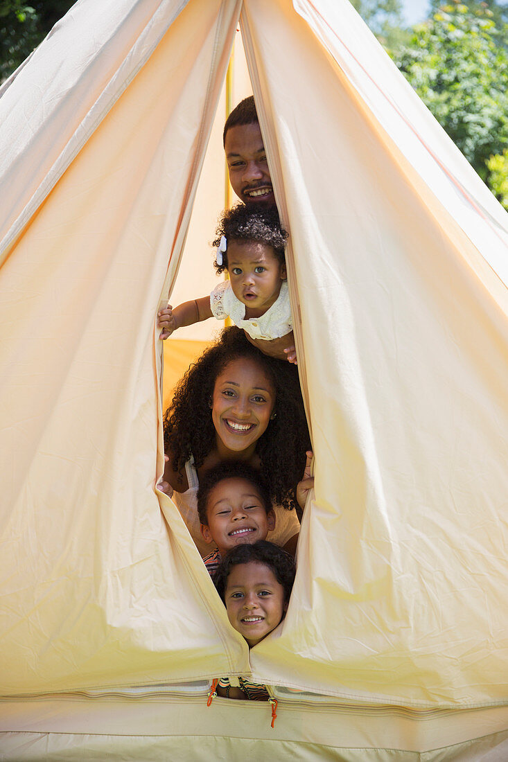Portrait playful family peering from inside tent