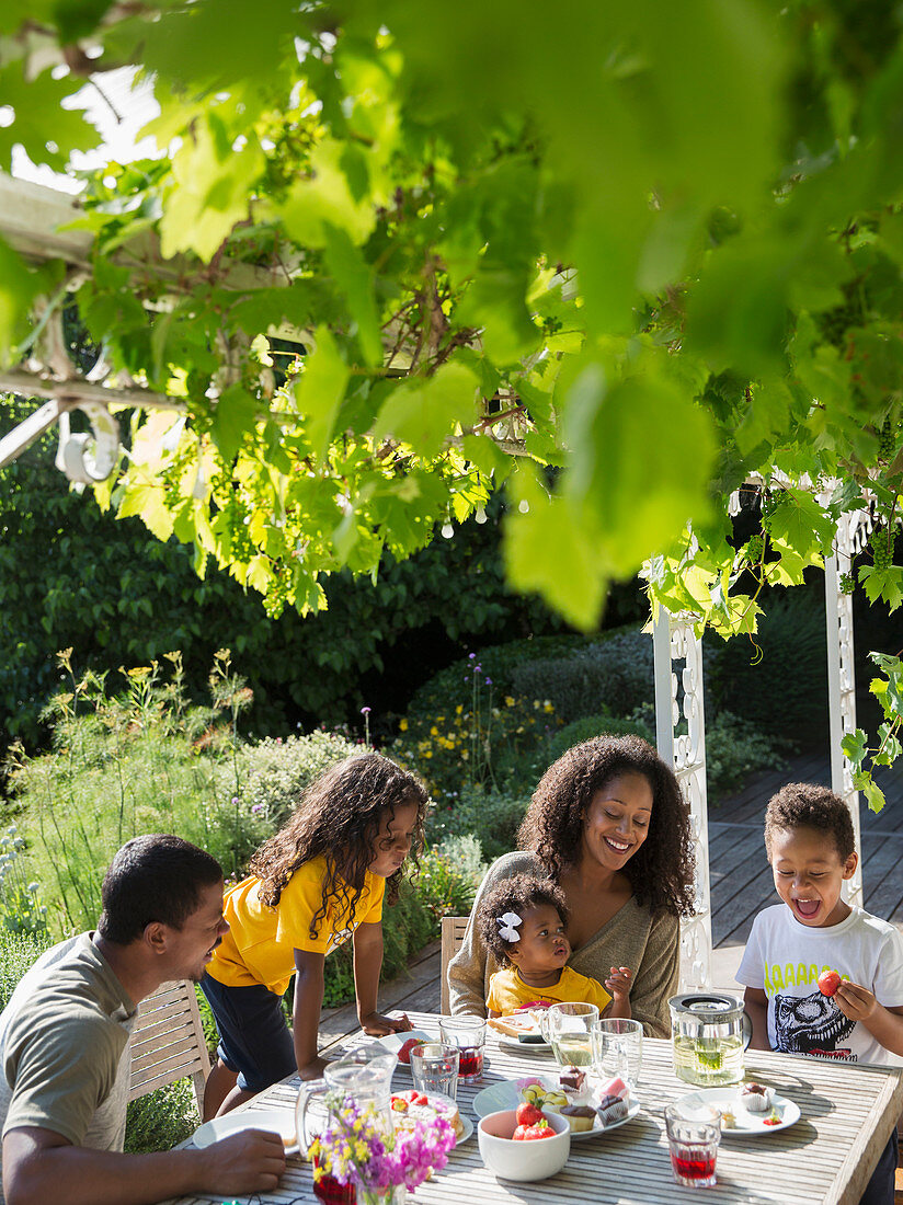 Happy family enjoying lunch at summer garden table