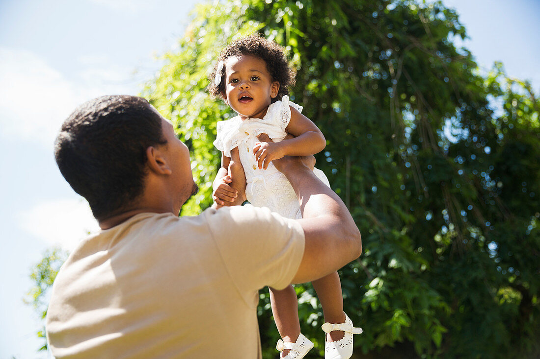 Father lifting toddler daughter overhead