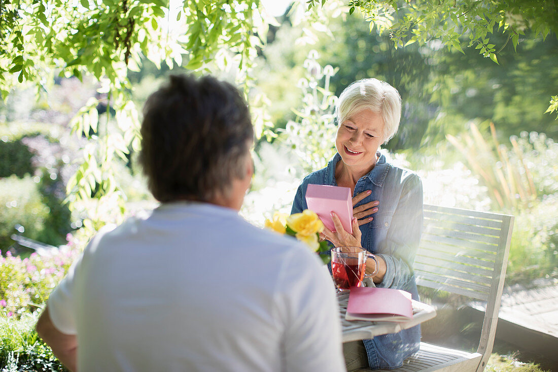 Senior woman opening gift from husband