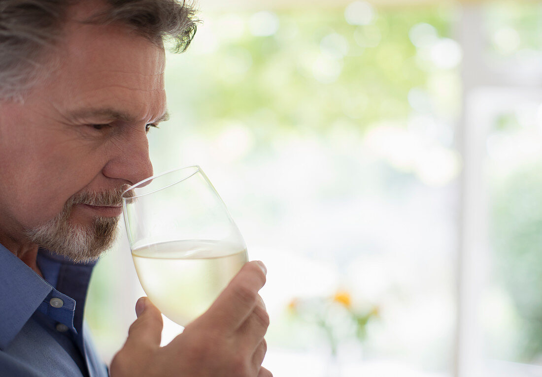 Senior man smelling and tasting white wine