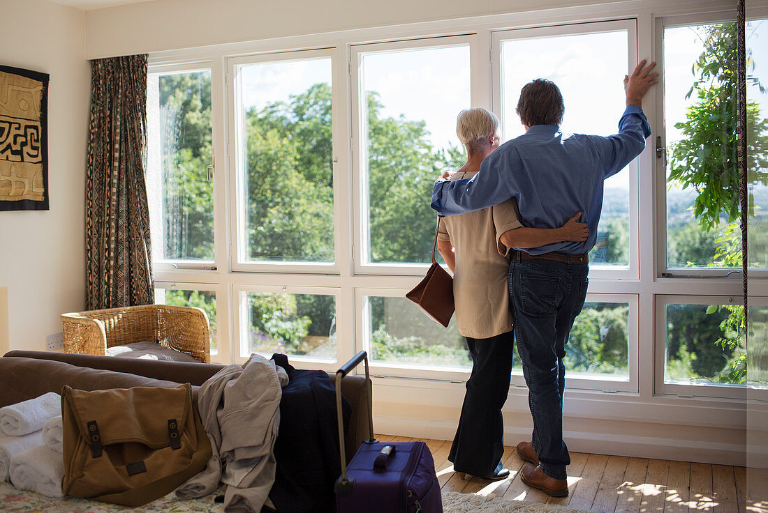 Senior couple hugging at house rental window