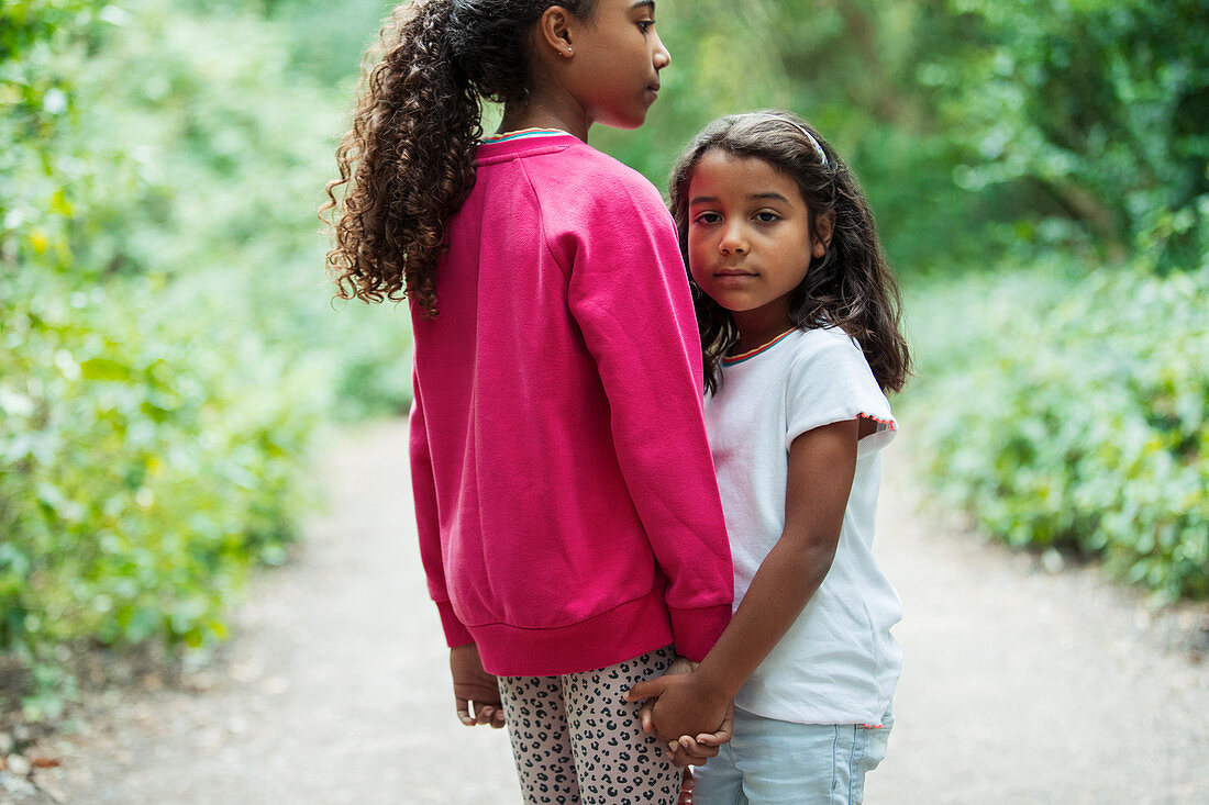 Sisters holding hands on park path