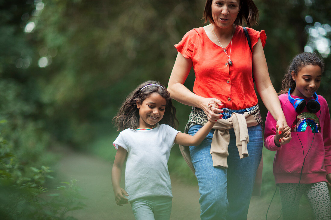 Mother and daughters hiking on trail in woods