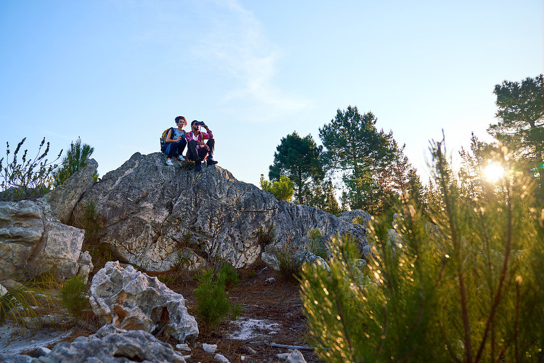 Young hiking couple relaxing on rock in nature
