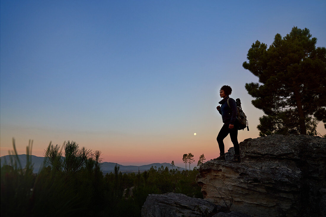Young female hiker on rock in desert at dusk