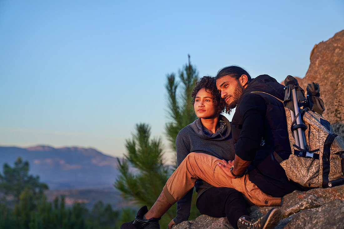 Serene hiking couple enjoying sunset on rocks