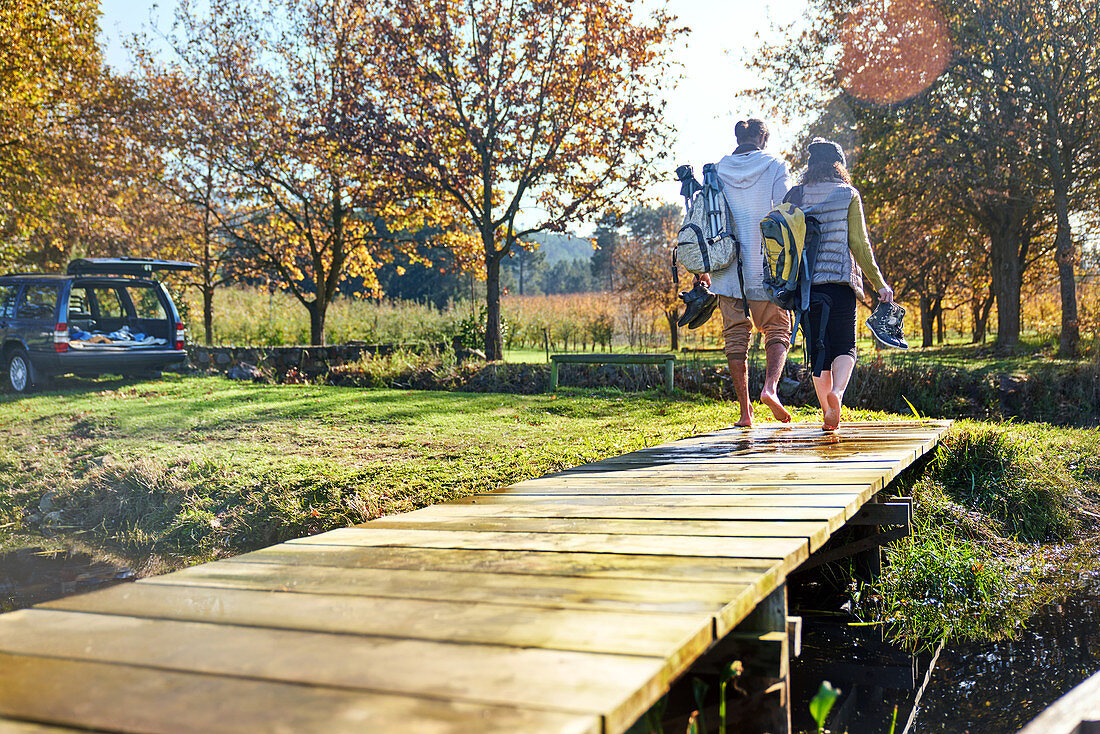 Barefoot couple walking on autumn lakeside dock