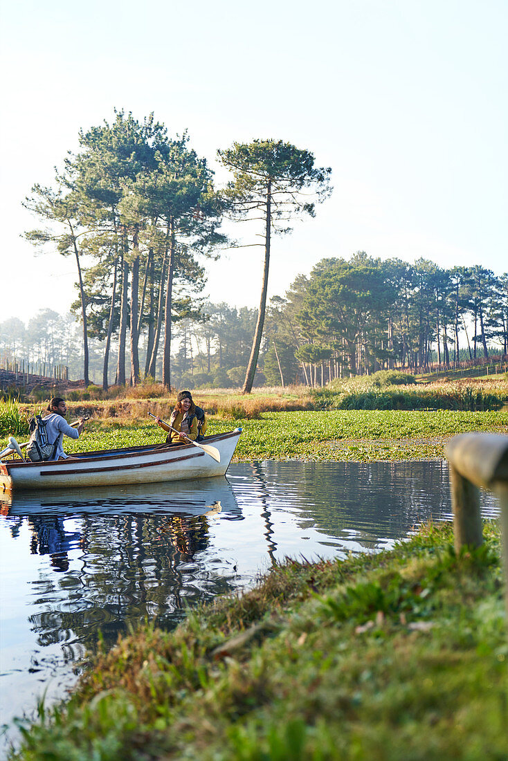Young couple in rowboat on sunny tranquil pond