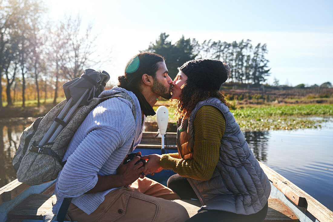 Couple kissing in rowboat on autumn lake