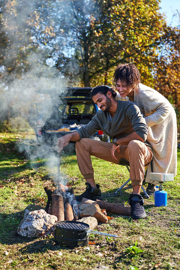 Happy couple enjoying campfire in autumn field