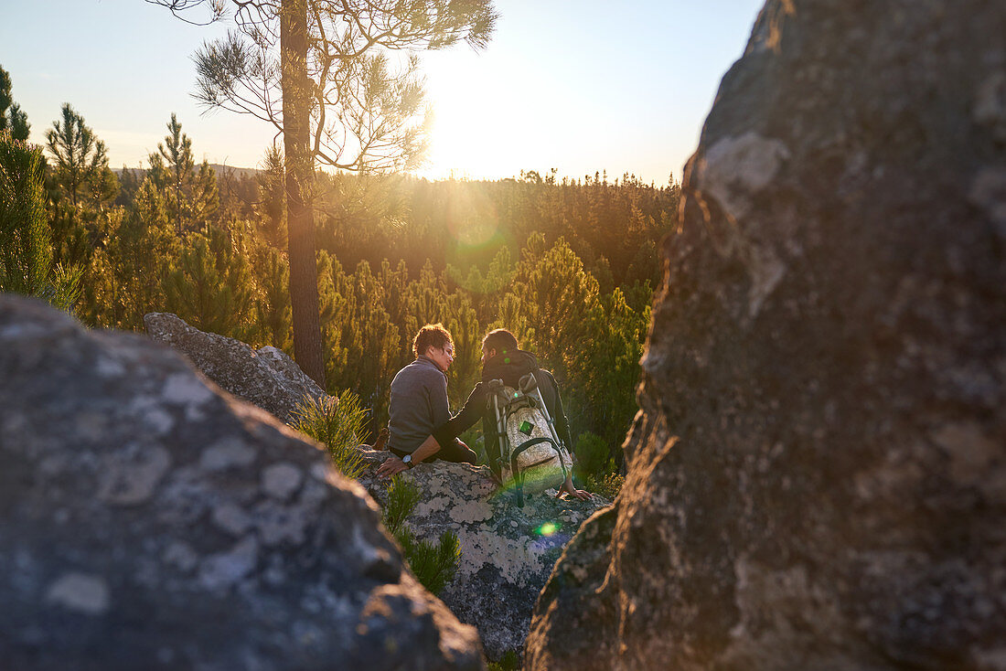 Hiker couple relaxing on rock in sunset woods
