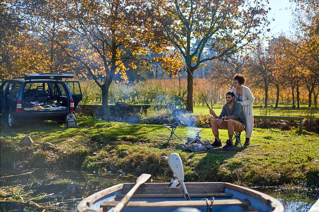 Happy couple fishing at sunny autumn riverside