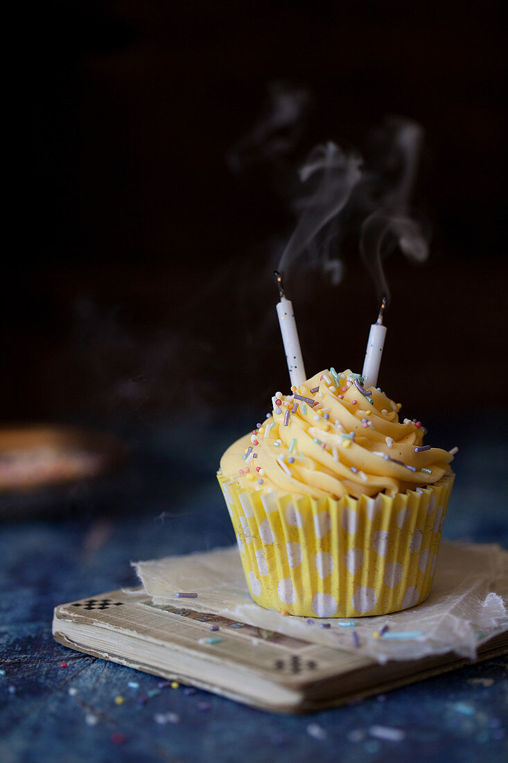 Cupcake mit Buttercreme und rauchenden Kerzen