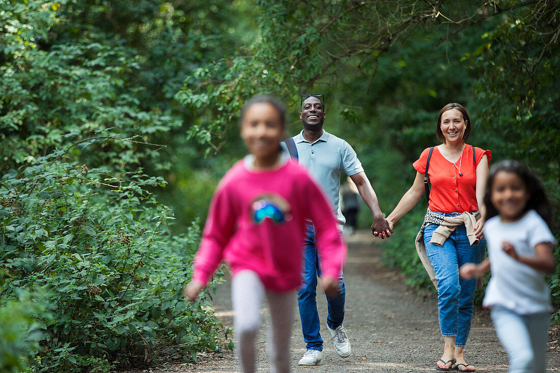 Happy family walking and running on path in woods