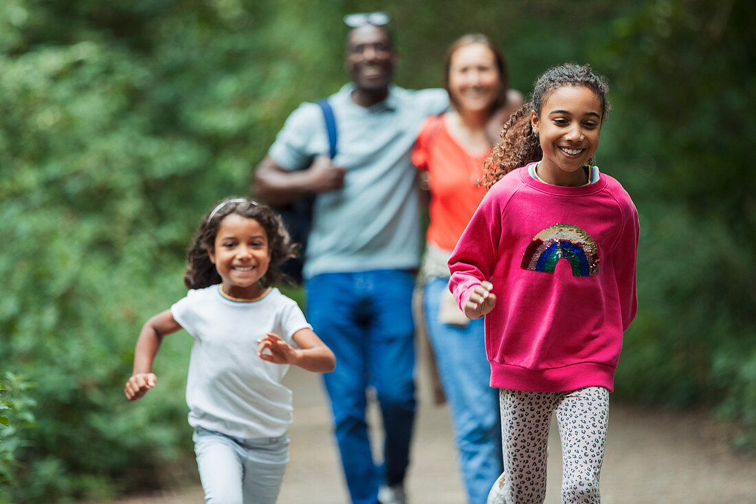 Happy family running and walking on path in woods