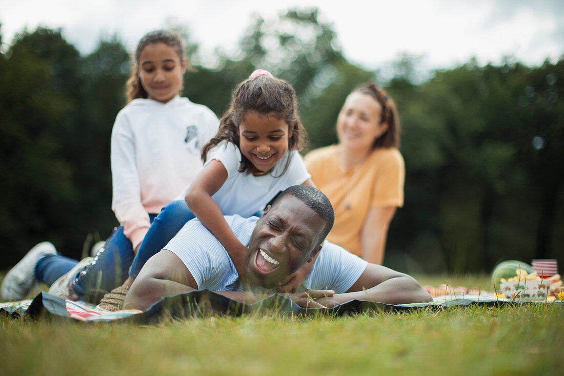 Happy playful family on picnic blanket in park