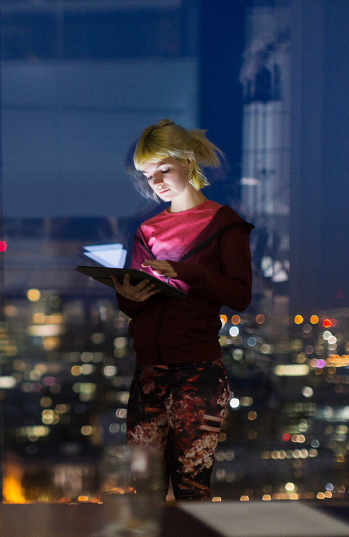 Young businesswoman with tablet at office window