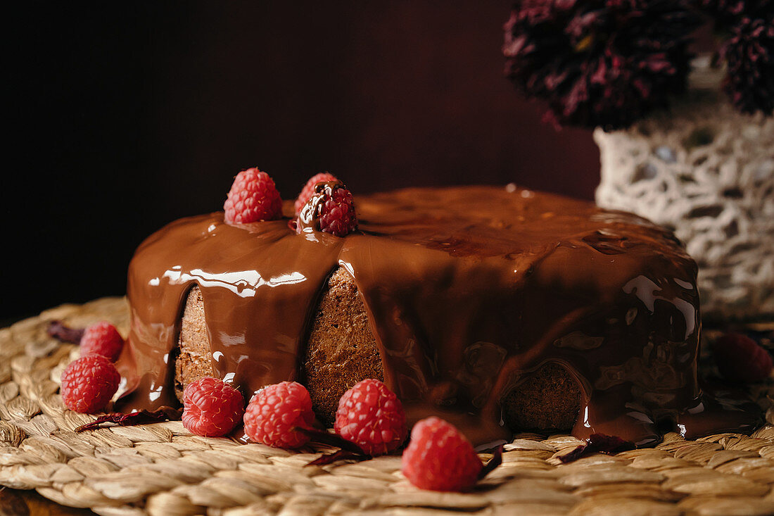 Appetizing homemade heart shaped cake with chocolate topping and fresh raspberries